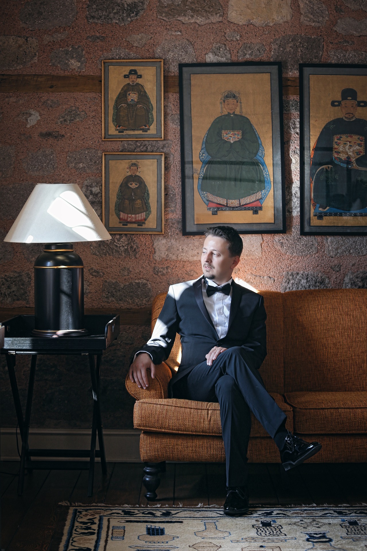 Man sitting elegantly in a suit with framed art on the wall