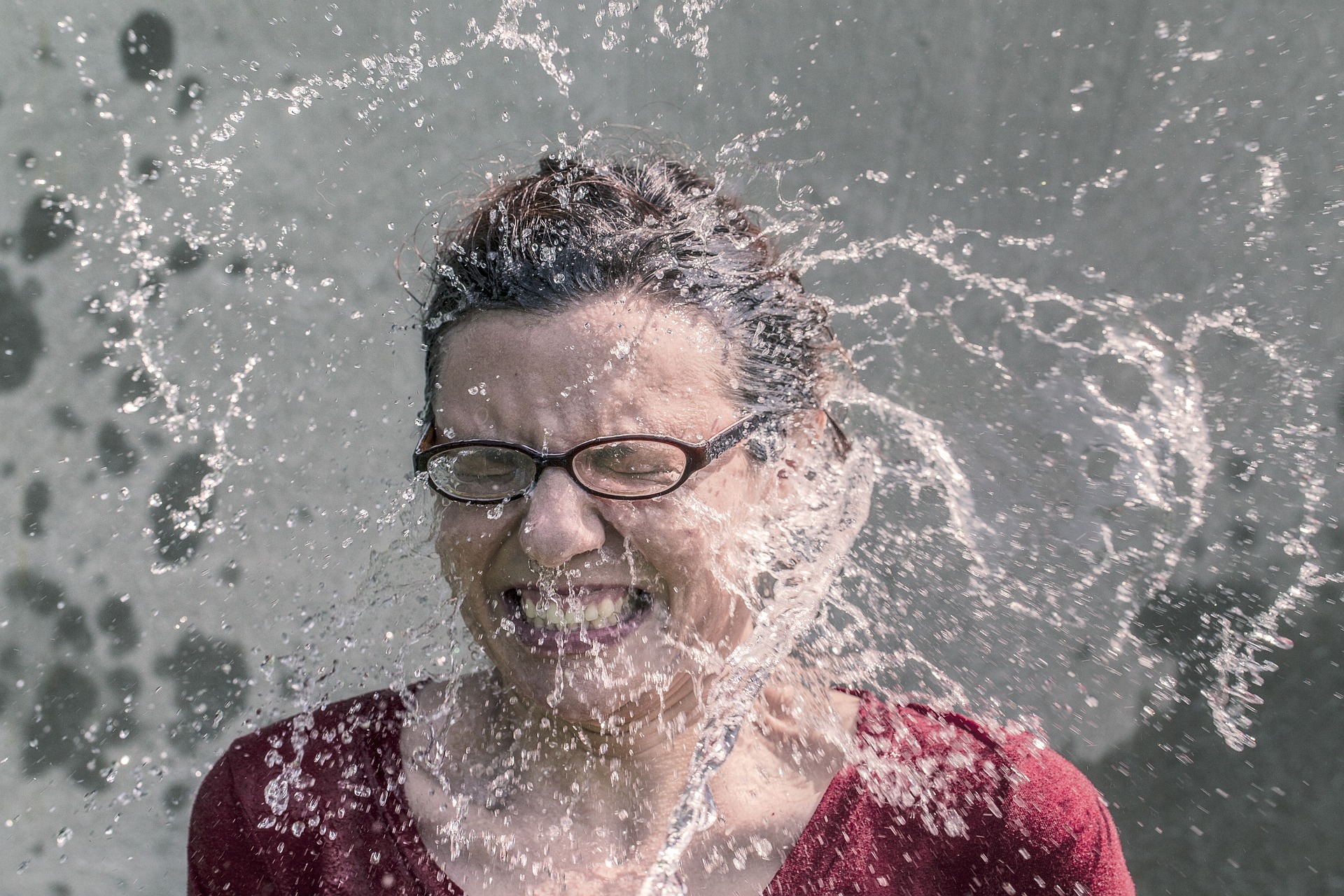 Woman splashed with water, smiling with glasses