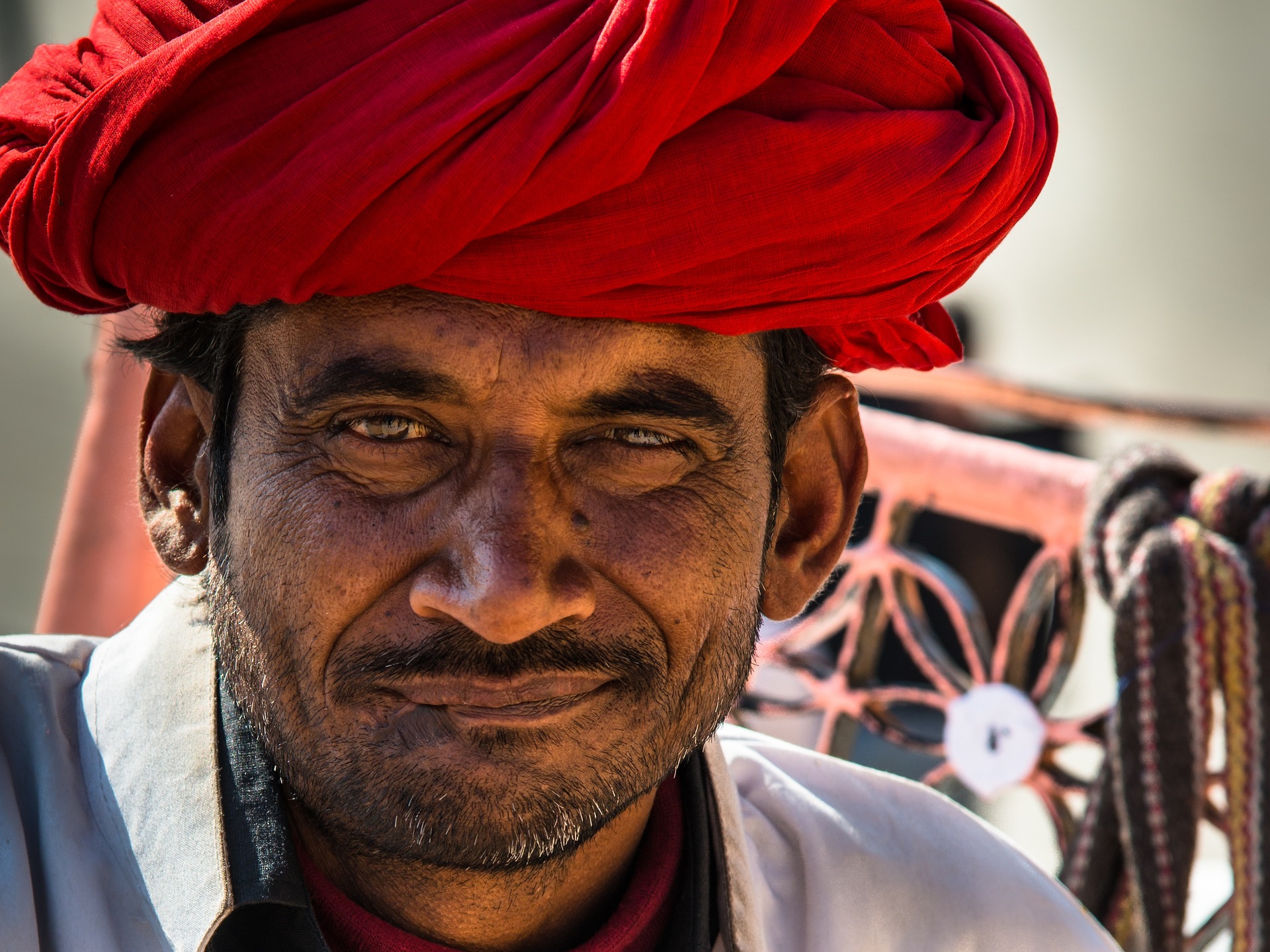 Man wearing a red turban smiling outdoors